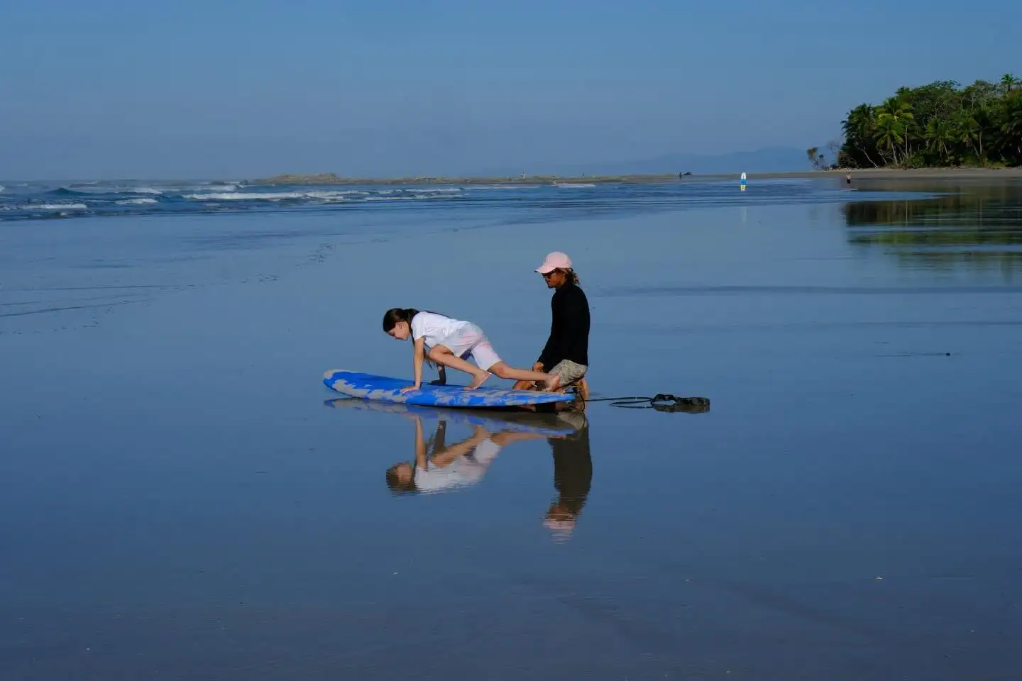Instructor coaching a student on the pop-up at sunrise on a calm beach