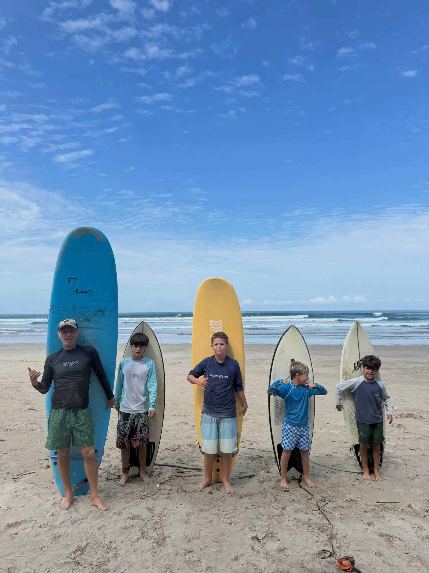 Kids and their instructor holding surfboards on the beach in Santa Teresa