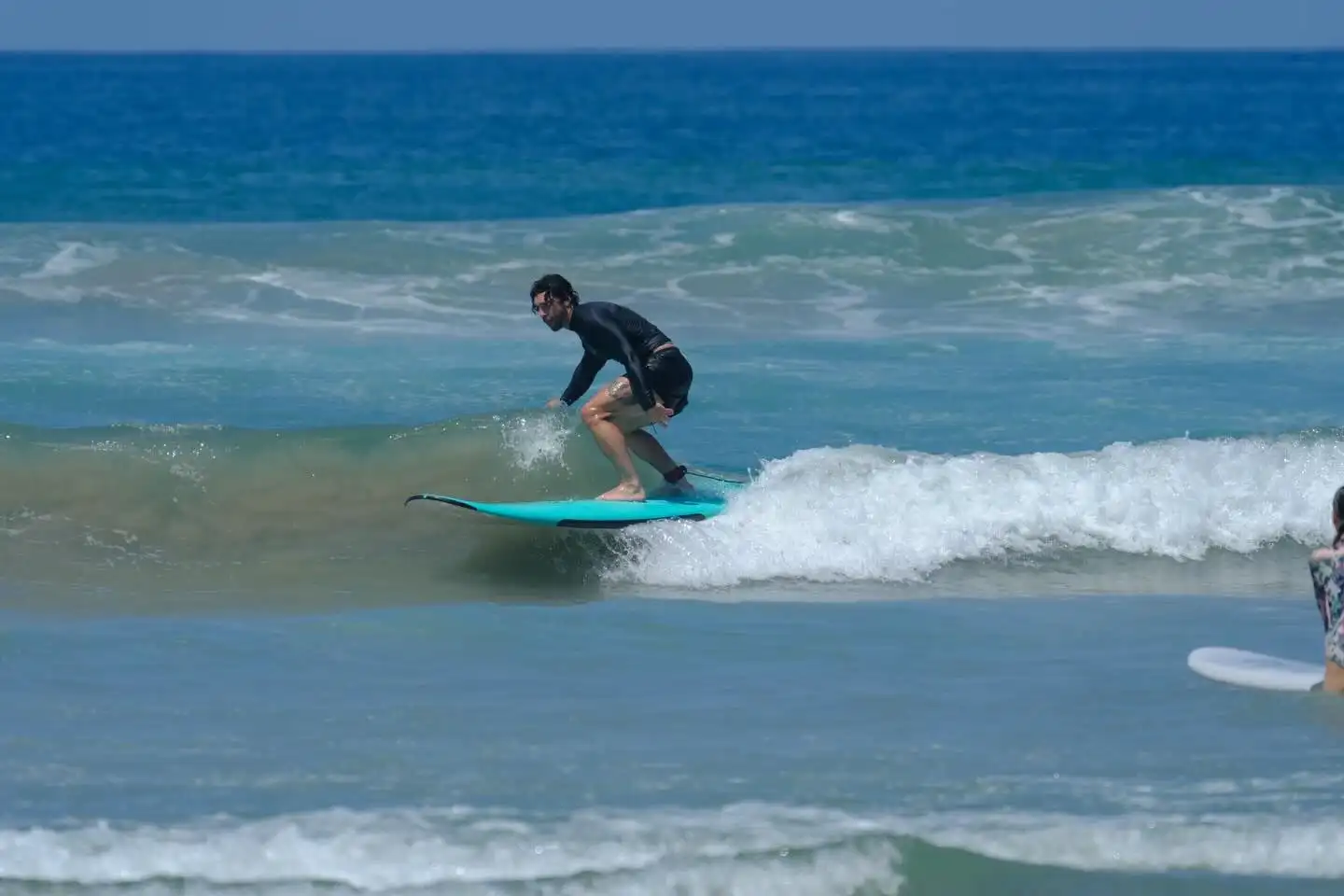 Surf student riding a wave on a soft-top board during a lesson in Santa Teresa, Costa Rica